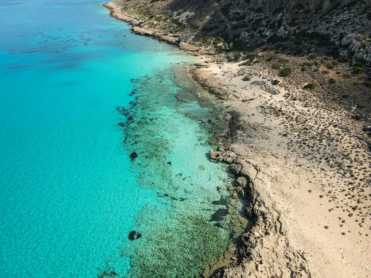 Turkuaz deniz ve kayalık kıyının havadan görünümü; temsili görsel